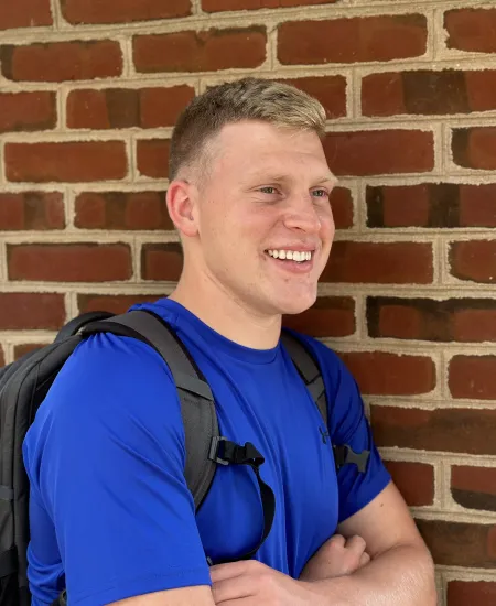 a person wearing a backpack standing in front of a brick wall