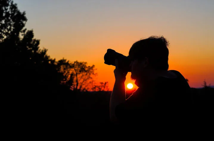 University of Kentucky journalism student Samuel Colmar lines up a shot at sunset during the Picture Kentucky Photojournalism Workshop in Frankfort, Kentucky, on Oct. 12, 2023. Photo by Carter Skaggs.