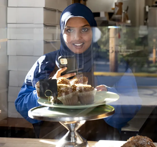 Employee Roukiya Ahamoud photographs pumpkin muffins to use as a post on the company’s Instagram account on Friday, Oct. 13, 2023 at Andy’s Artisan Bread in Frankfort, Kentucky. Photo by Gracie Moore.