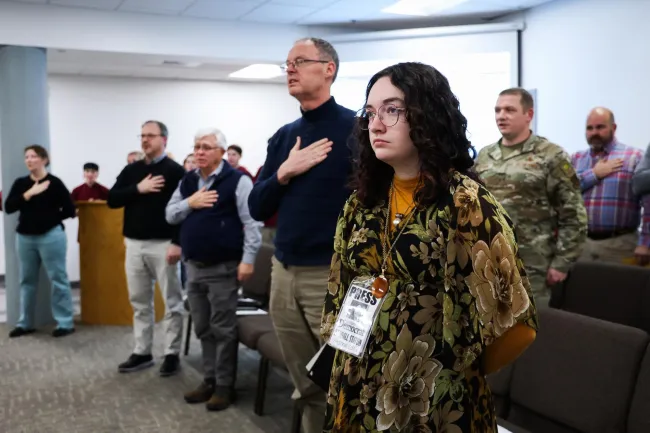 Cynthiana Democrat Regional Editor Kendall Staton stands for the Pledge of Allegiance on Tuesday, Jan. 23, 2024, during a school board meeting in Cynthiana, Kentucky. In public meetings where members pray or pledge, Staton chooses not to participate to maintain journalistic boundaries. Photo by Abbey Cutrer.